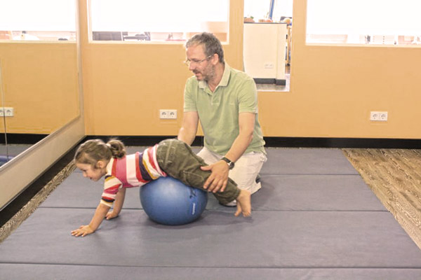 Physiotherapie Nils Hanke in einer Behandlung mit einem medzinischen Ball und einem Kinde
